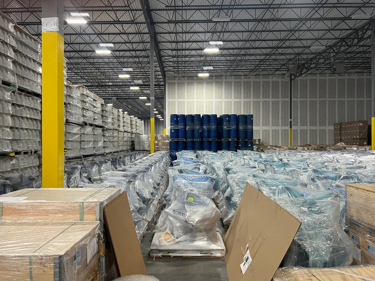 Warehouse interior with wrapped goods on pallets and blue drums
